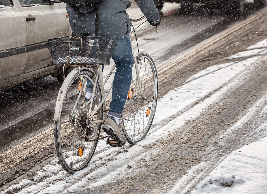 Radfahren im Winter Ein Radfahrer fährt auf einem ungeräumten Radweg durch Schnee.