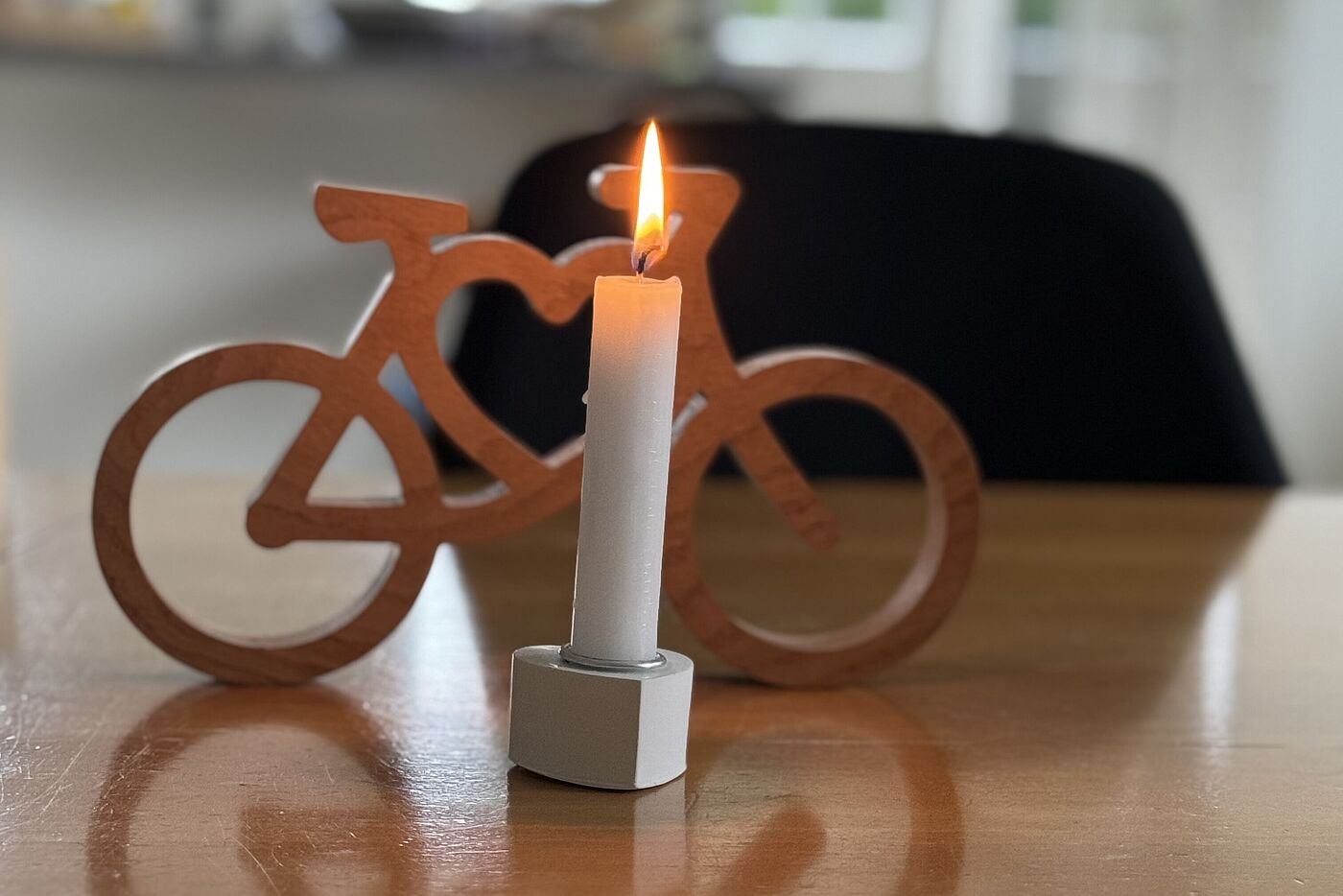 Miniatur-Fahrrad und angezündete Gedenkkerze 