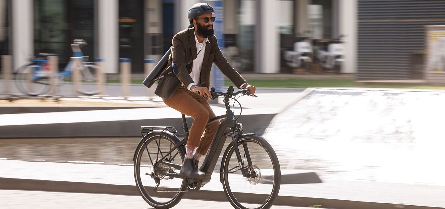 Ein Pendler fährt auf seinem elektrischen Fahrrad durch das Stadtgebiet. 